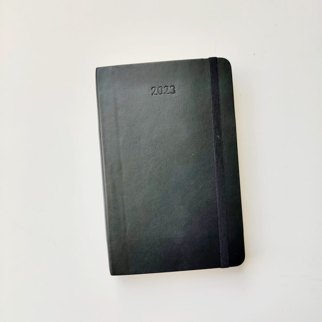 A black Moleskine pocket planner with 2023 embossed on the cover.