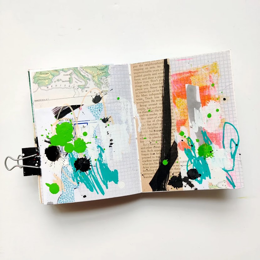 An open mixed media art journal. The pages are covered in a layer of collage, and on top of that are energetic marks in black, teal, bright green, and white. Most of the background peeks through.
