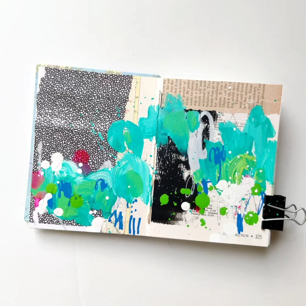 Open mixed media art journal. A layer of neutral-colored collage is covered with energetic marks in teal, green, white, and green. Much of the background shows through.