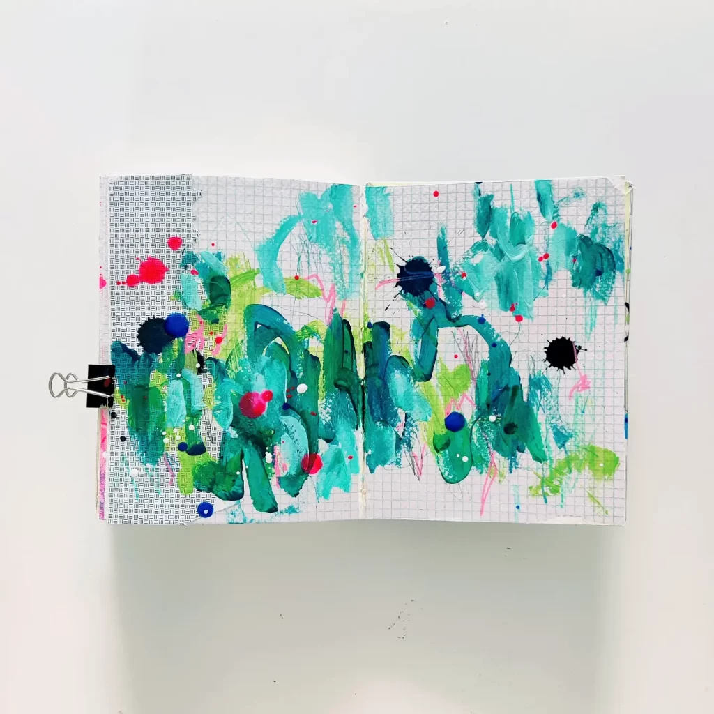 Open mixed media art journal. A layer of collage (graph paper, security envelope) is topped with energetic abstract marks in teal and turquoise, green, neon pink, and dark blue. Much of the background shows through.