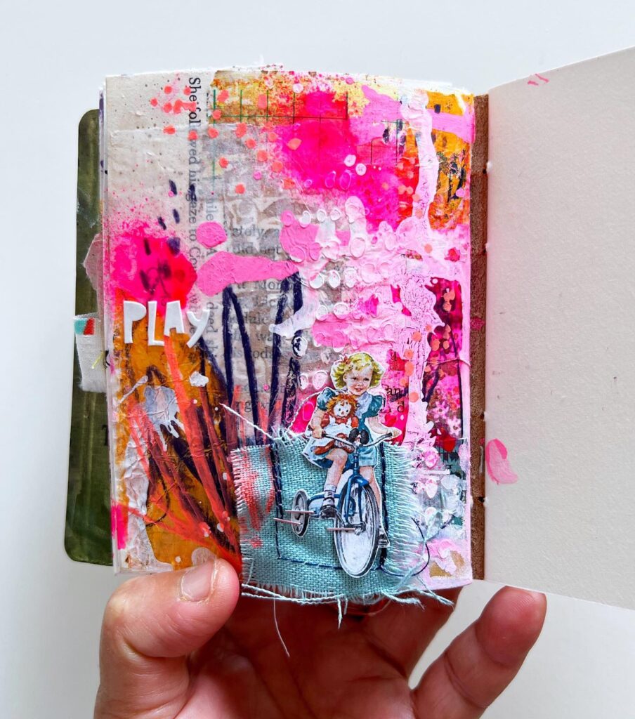 Mixed media art journal page in shades of bright pink, blue, and whites.