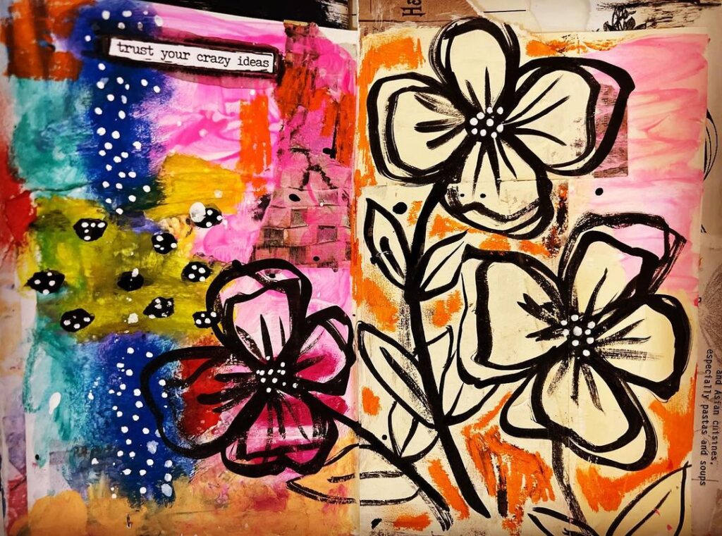 An open art journal page. To the right are sketch-like flowers drawn in black; to the left are blues and pinks.