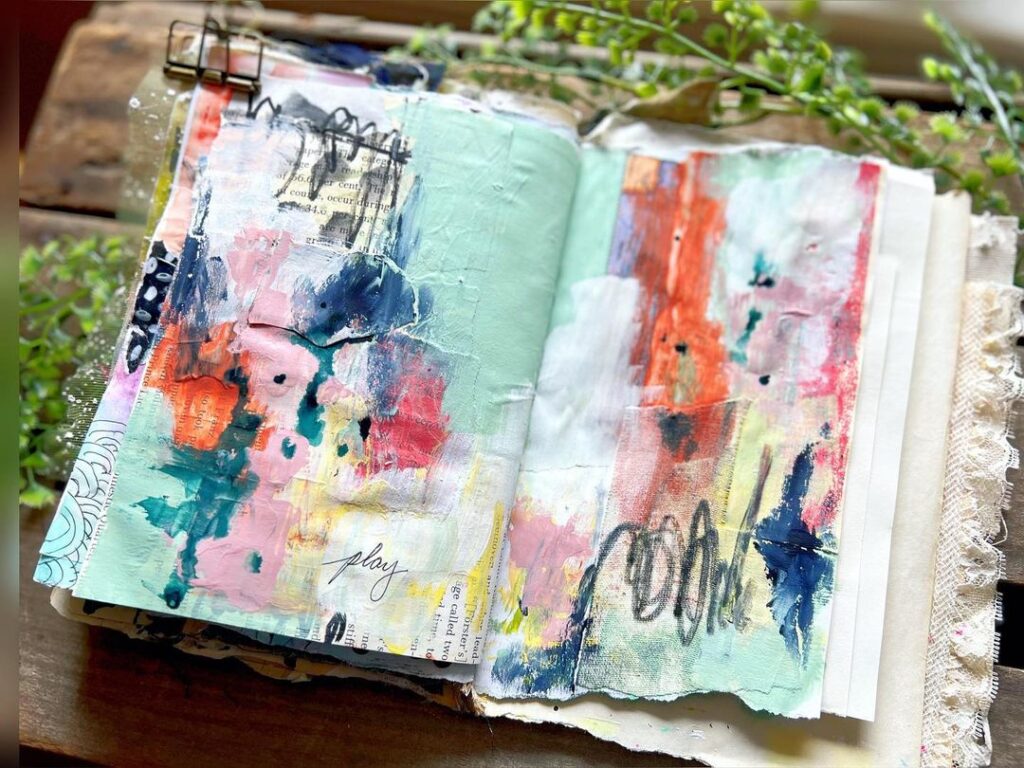 Open mixed media art journal page in shades of blues and reds.