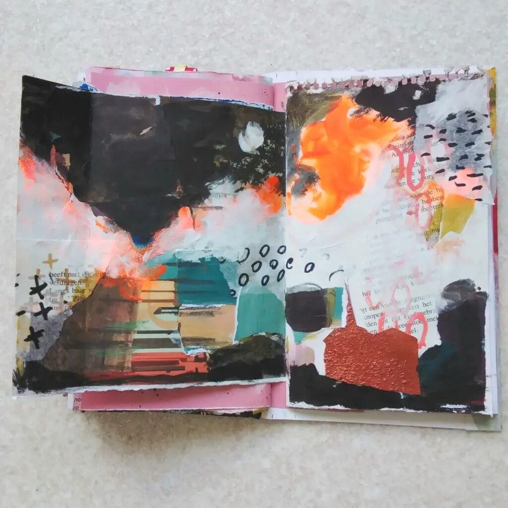 An open mixed media art journal with elements of white, black, blue, red, pink, and orange.