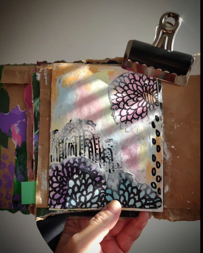 Mixed media art journal page. A pastel background is topped with rounded doodles in black.