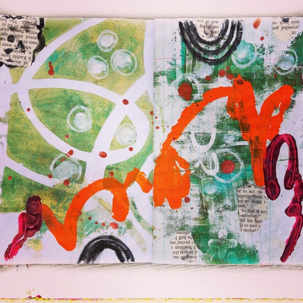 Open mixed media art journal. A layer of collage is covered in doodles and scribbles; the primary colors are green, orange, blue, and black.