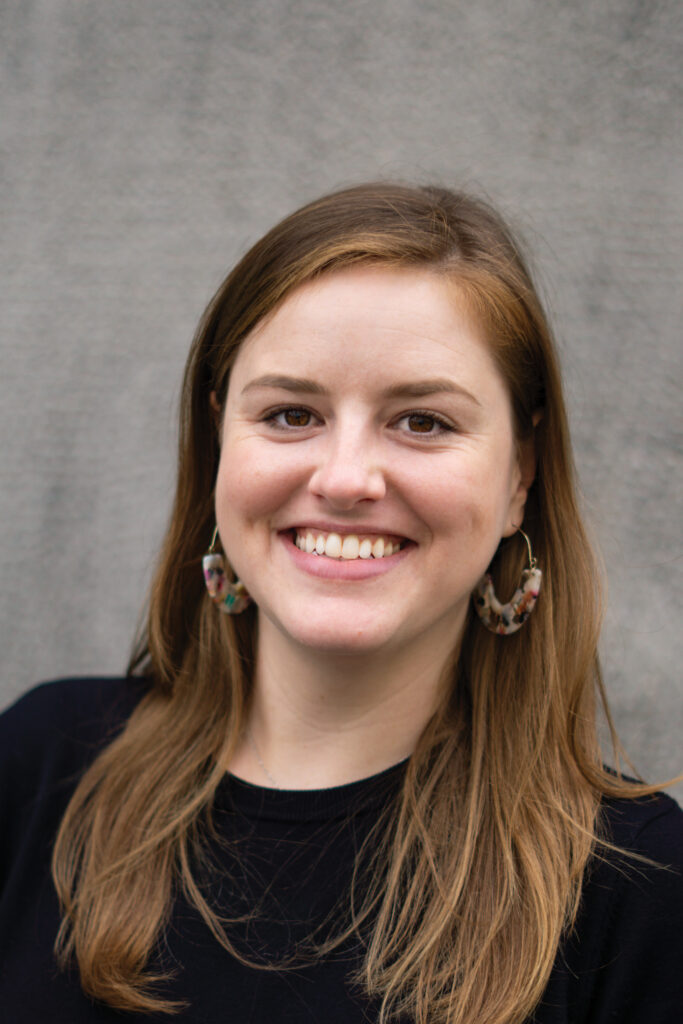 A smiling white woman — Ingrid Murray. She is wearing a black top and has brown eyes and long reddish-brown hair.